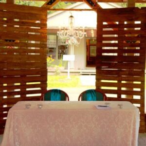 A table with two chairs and a chandelier in the background.