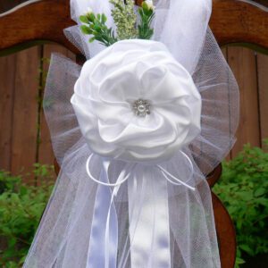 A white bow with flowers and tulle on the back of a chair.