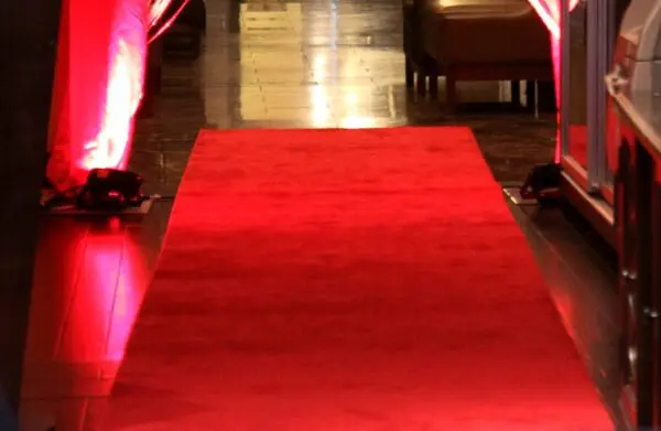 A red carpet is shown with two people walking on it.