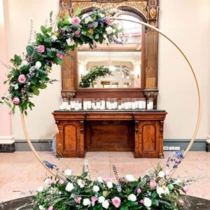 A large round wedding arch with flowers on top of it.