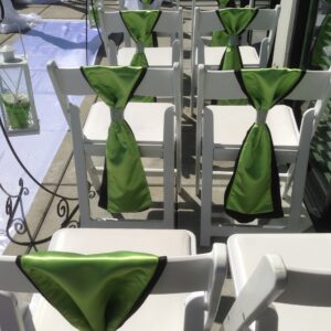 A row of white chairs with green ties on them.