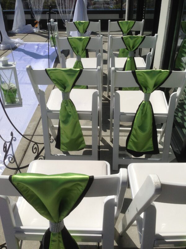 A row of white chairs with green ties on them.