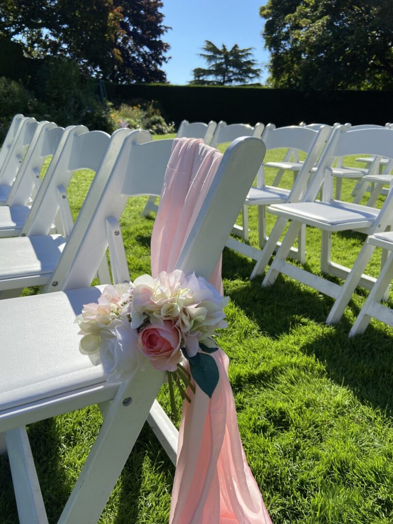 A row of white chairs with pink flowers on them.