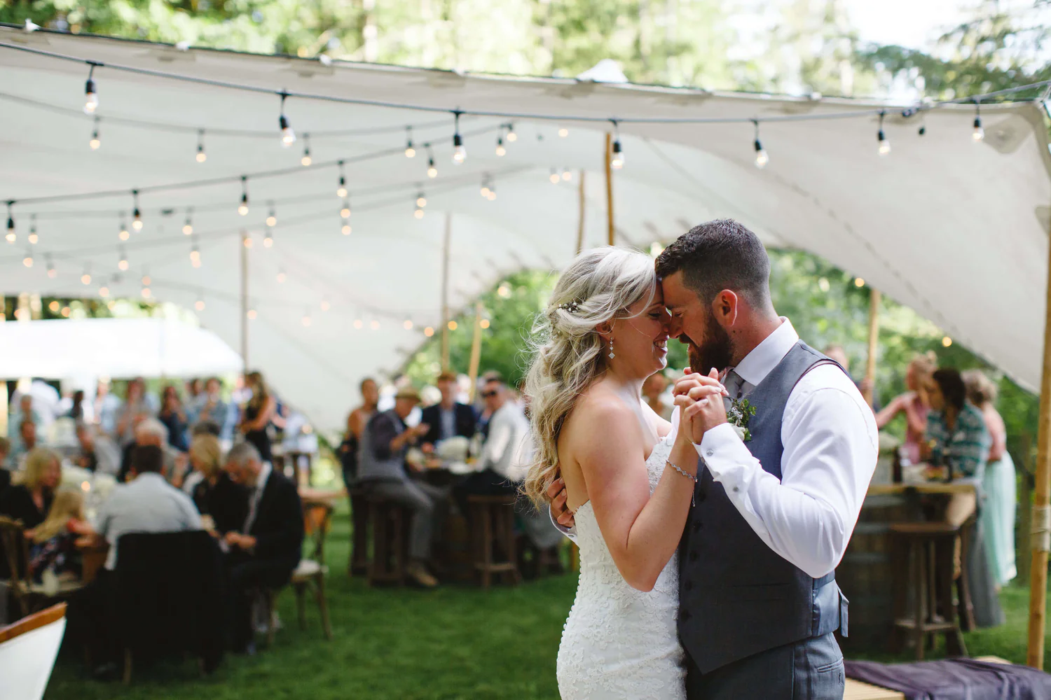 A bride and groom are dancing under an awning.