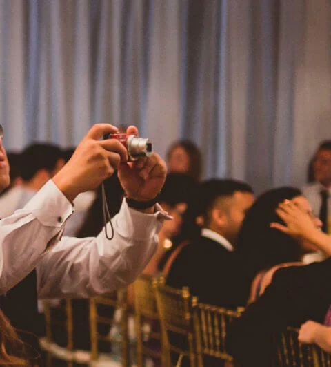 A man holding up a camera in front of other people.