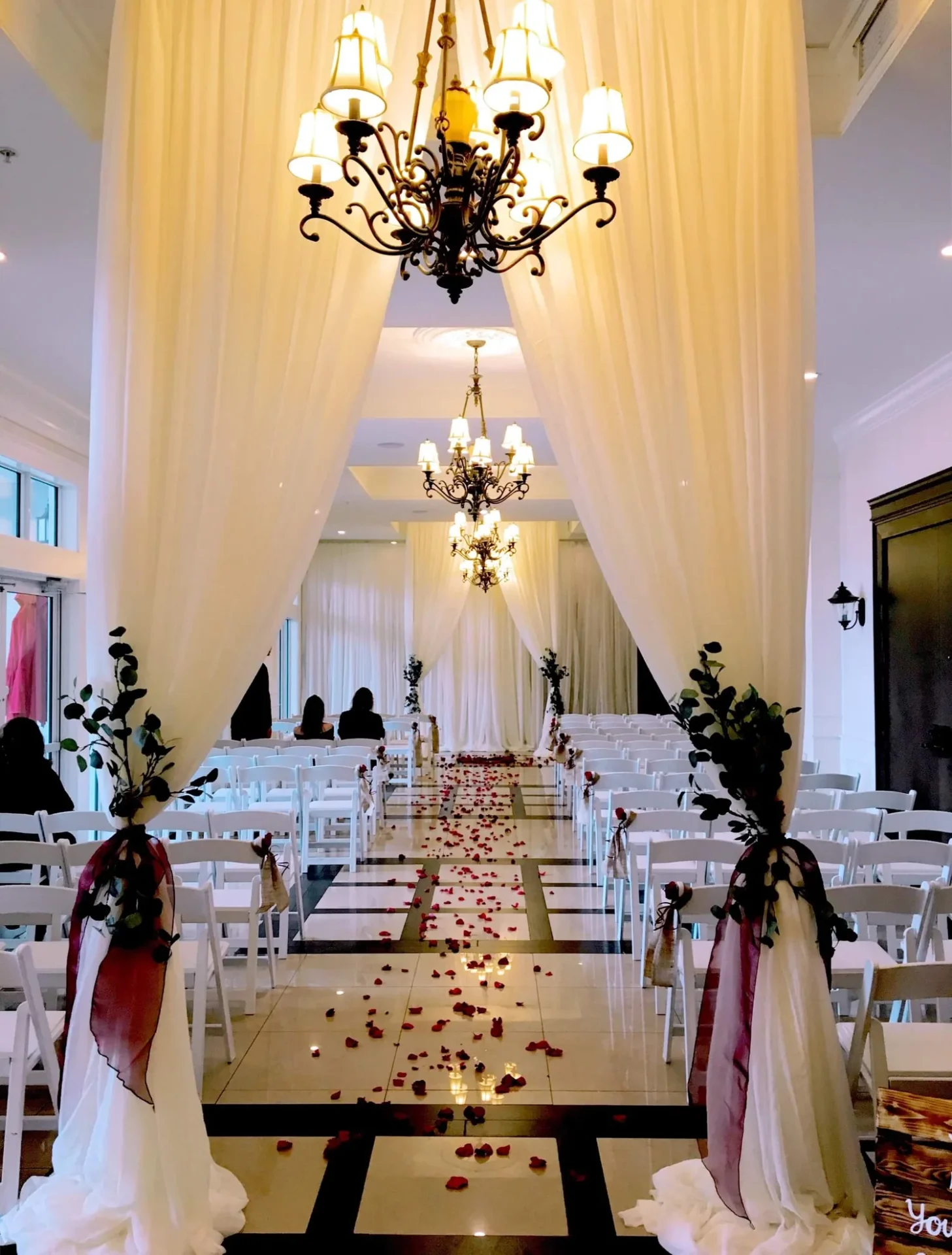 A wedding ceremony with white chairs and red flowers.