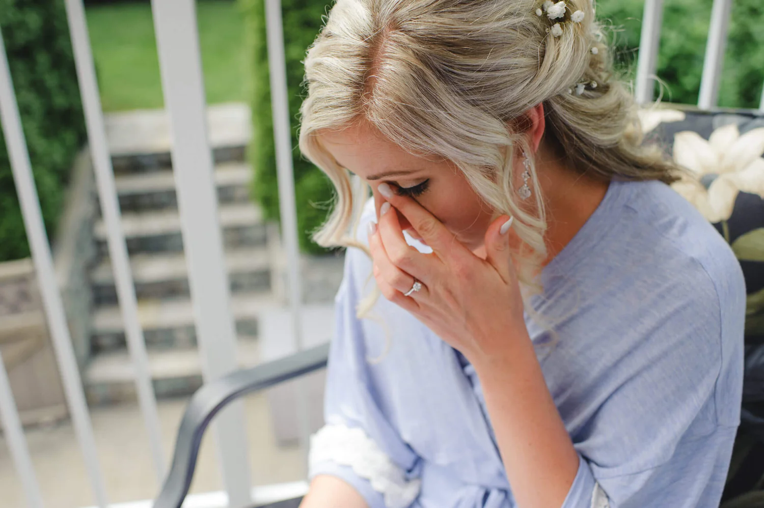 A woman sitting outside with her hand over her face.