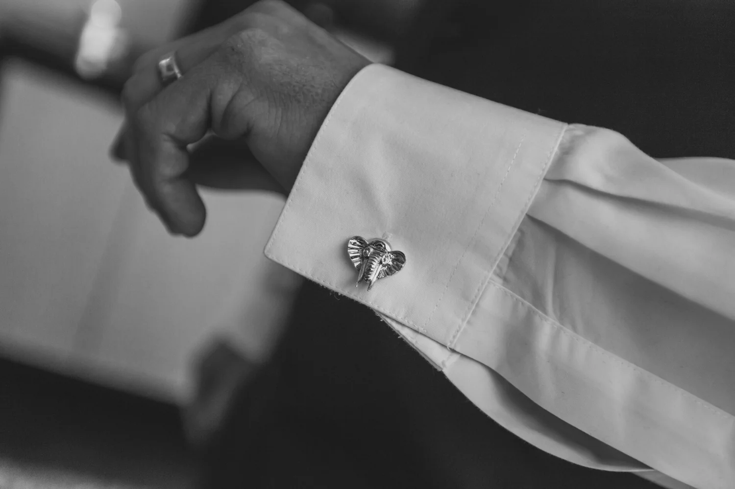 A man wearing a wedding ring and cufflinks.