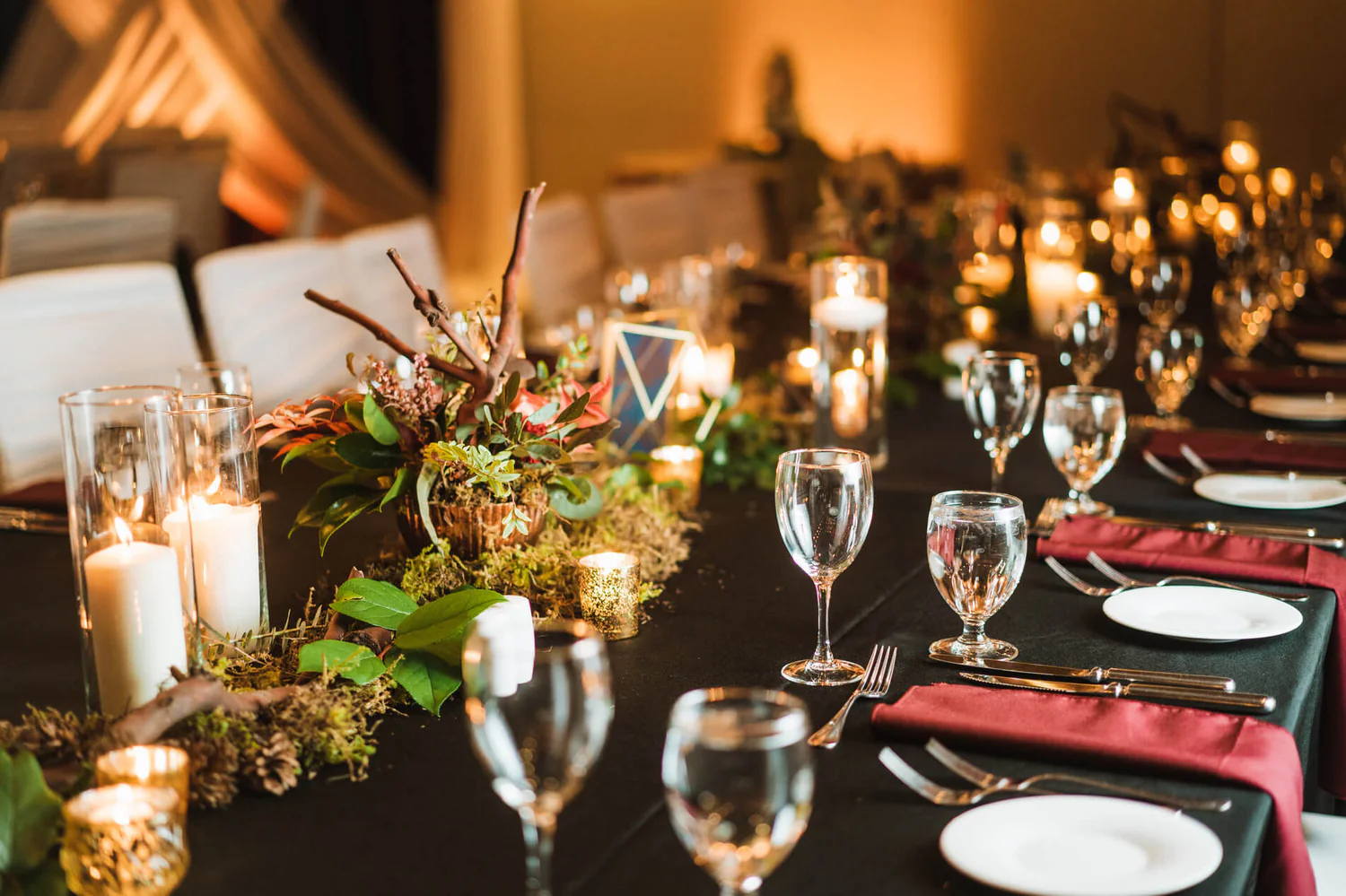 A table set with wine glasses and candles.