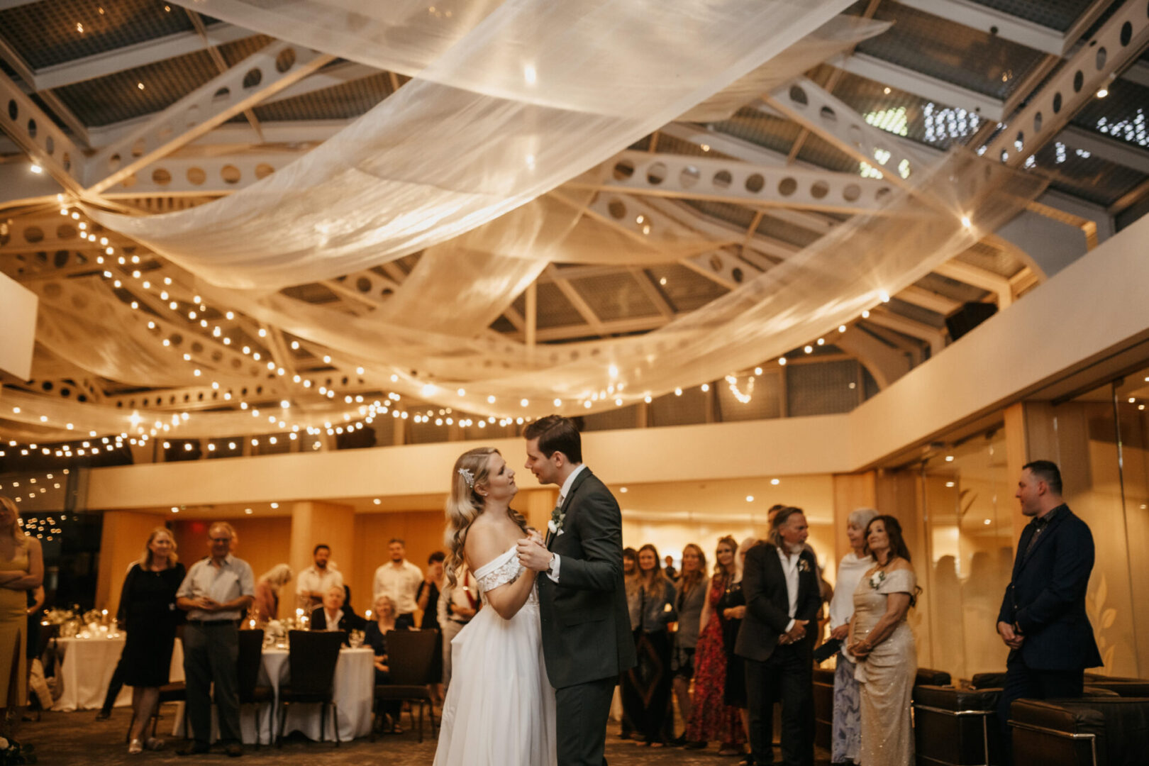 A bride and groom are dancing in front of the crowd.