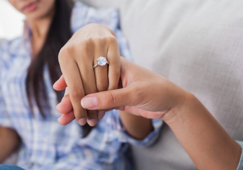 A woman is holding her wedding ring while someone holds it.