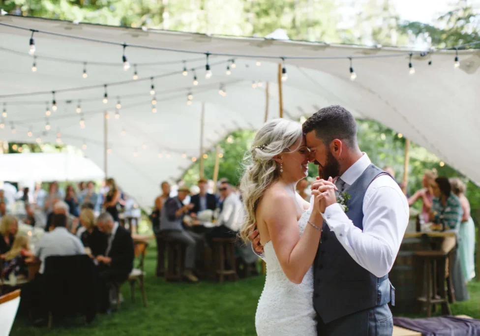 A bride and groom are dancing under an awning.