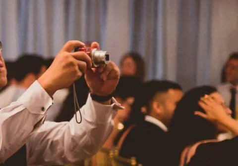 A man holding up a camera in front of other people.