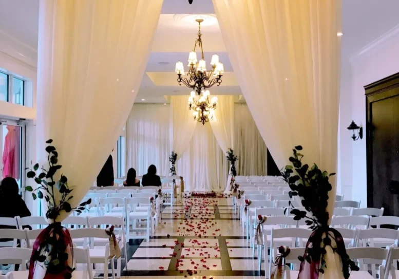 A wedding ceremony with white chairs and red flowers.