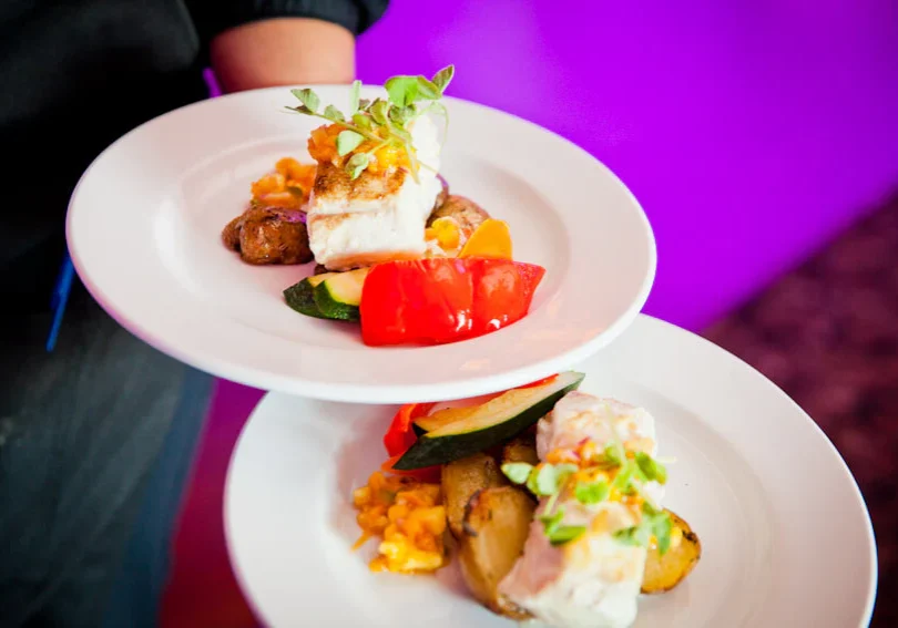 Two plates of food on a table with purple background.