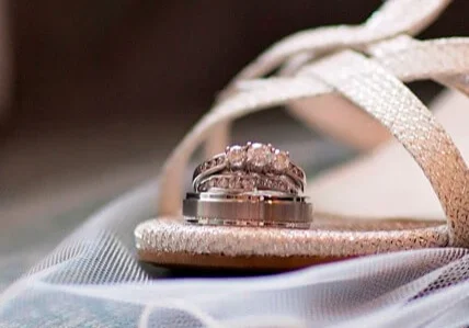 A pair of wedding rings sitting on top of a sandal.